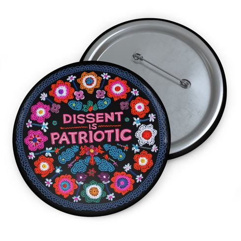 Round black pinback button with vibrant floral embroidery design surrounding bold pink and red text reading "Dissent is Patriotic."